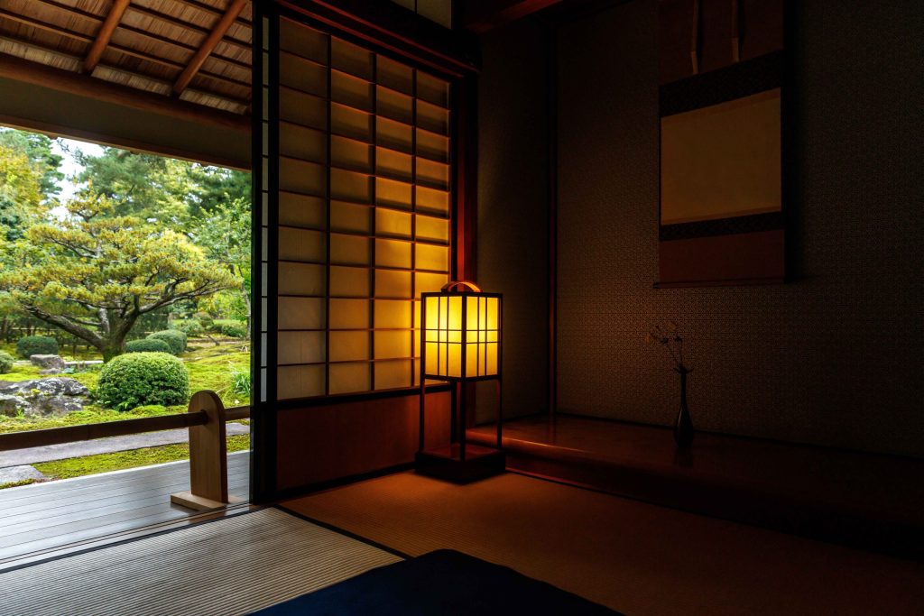 Traditional Japanese room with shoji screen, garden view, and soft lantern light