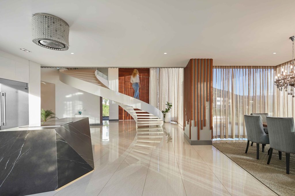 Bright contemporary interior with staircase and sheer drapery filtering sunlight