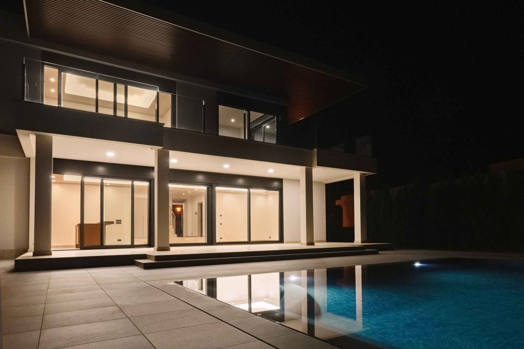 Contemporary house with a pool and large glazed openings, illuminated at night