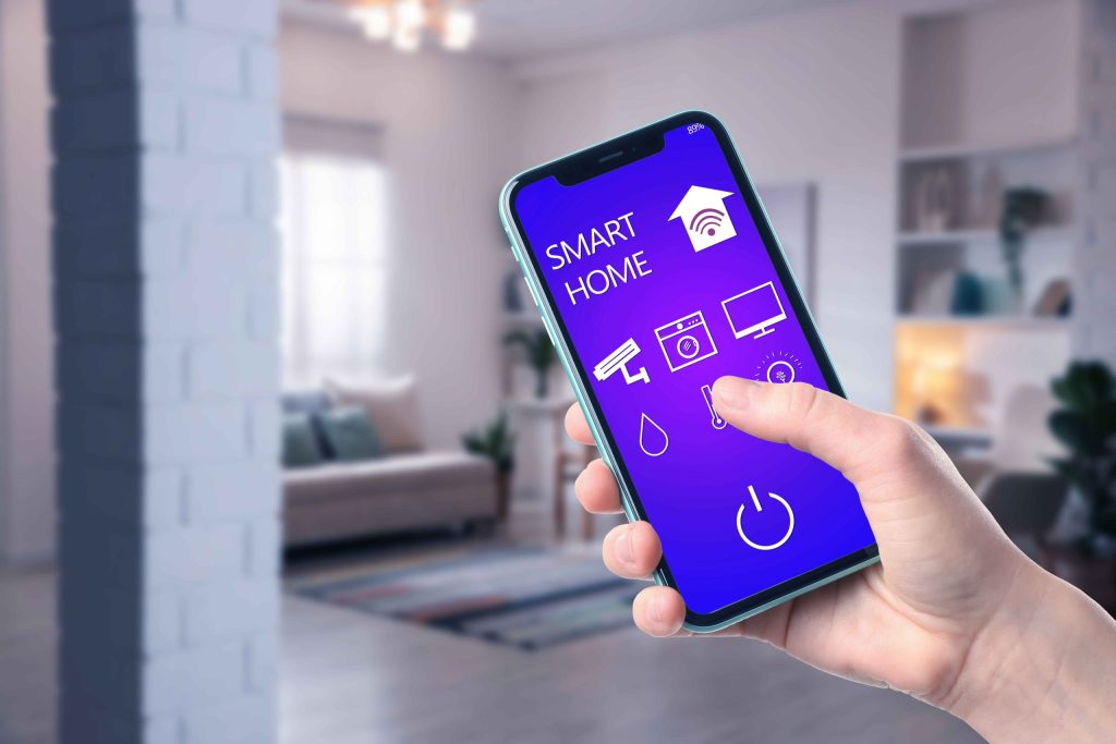 Close-up of a hand holding a smartphone showing smart home controls in a living room