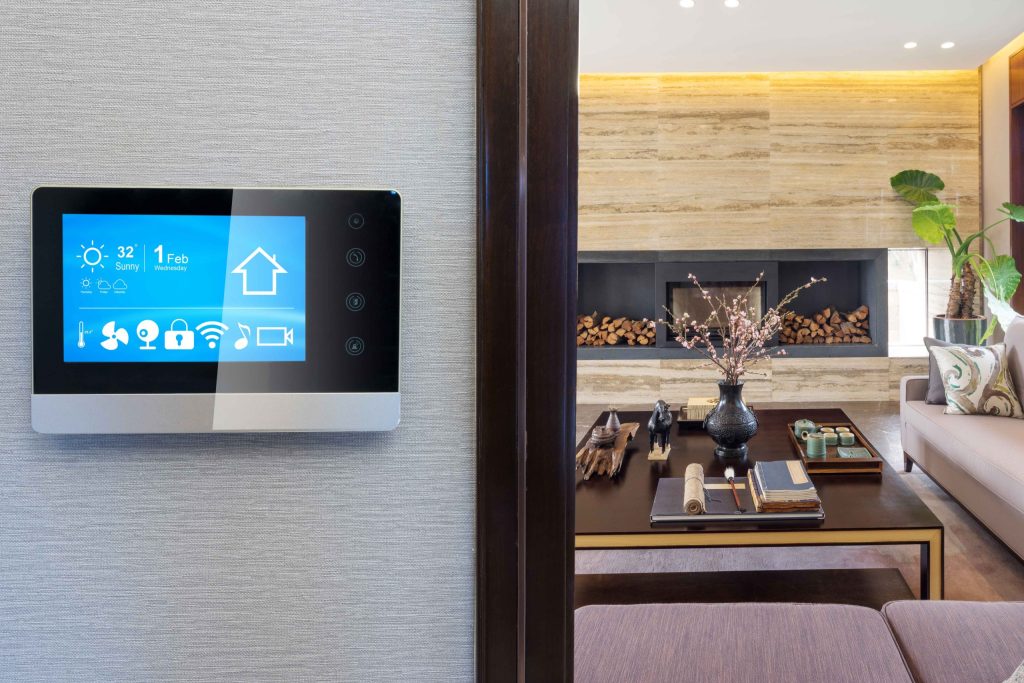 Wall-mounted smart home control panel beside a luxury living room interior
