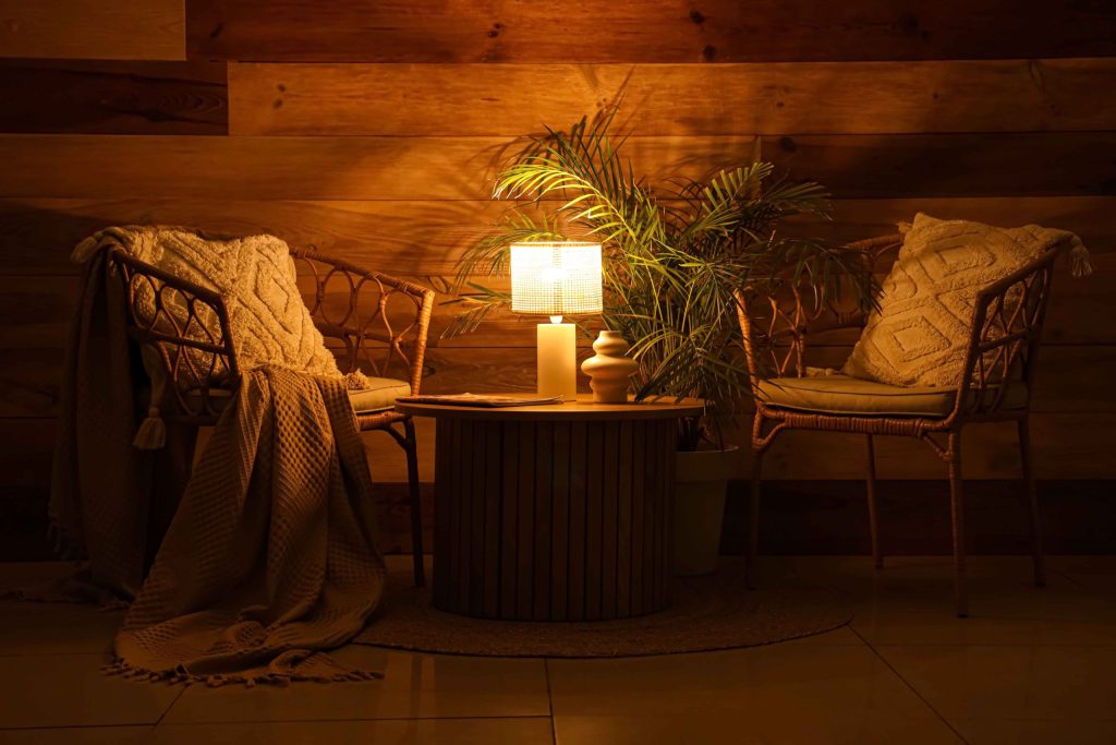 Cozy warm corner with table lamp, woven chairs, and wood wall