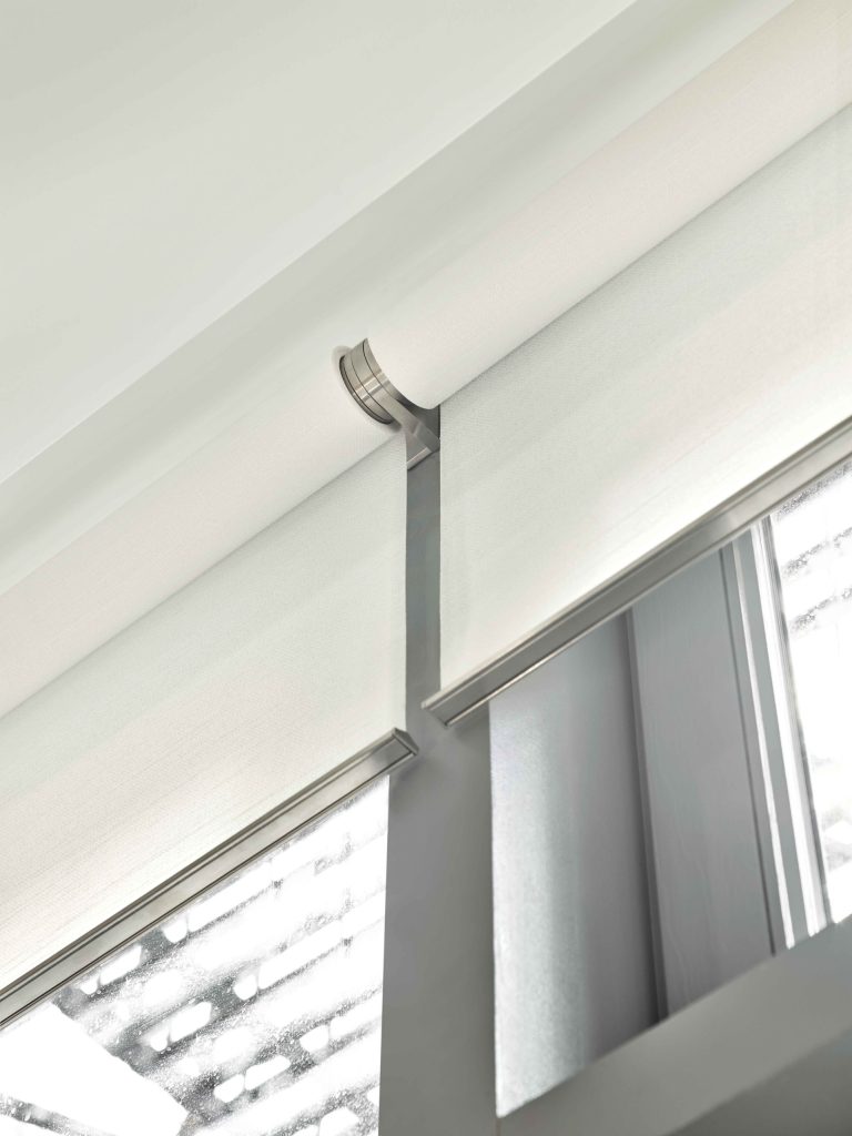 Close-up of dual roller shades and hardware near a window