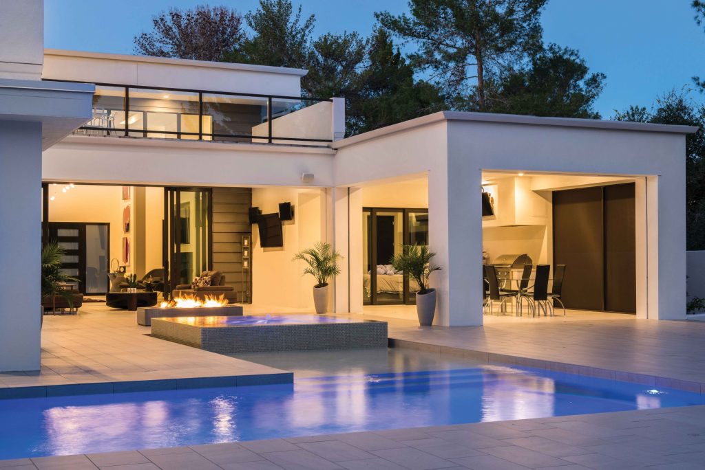 Modern luxury home with pool and outdoor living area at dusk