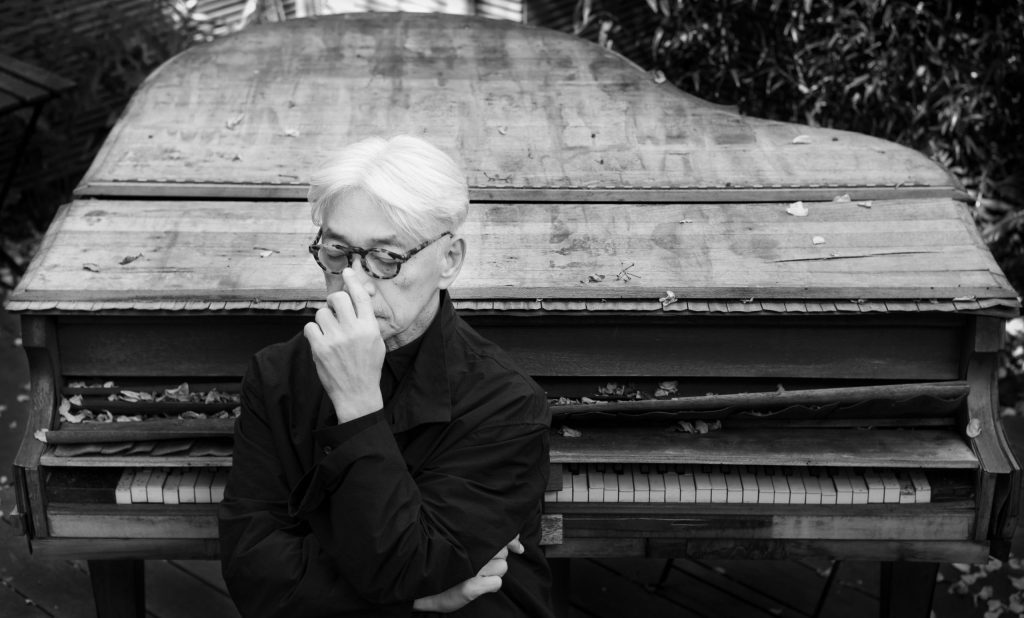 古いピアノの前で思索する坂本龍一を捉えたモノクロの公式ポートレート