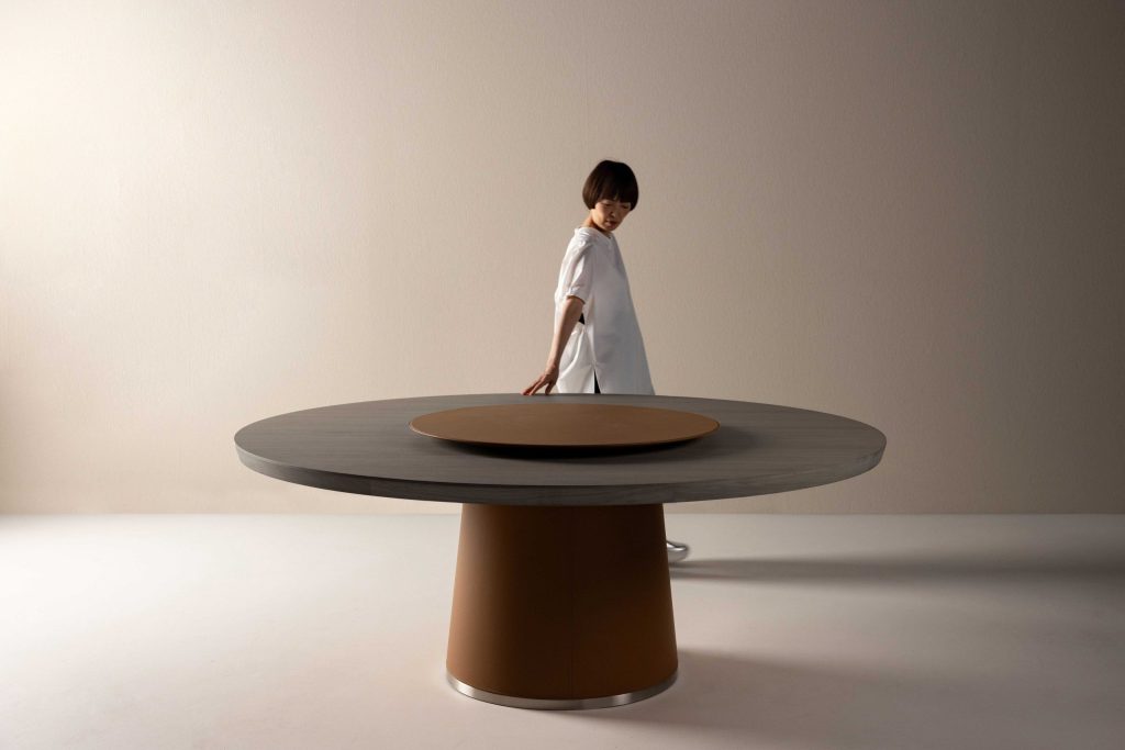 Flexform Enn round dining table designed by Fumie Shibata with a leather-clad pedestal base