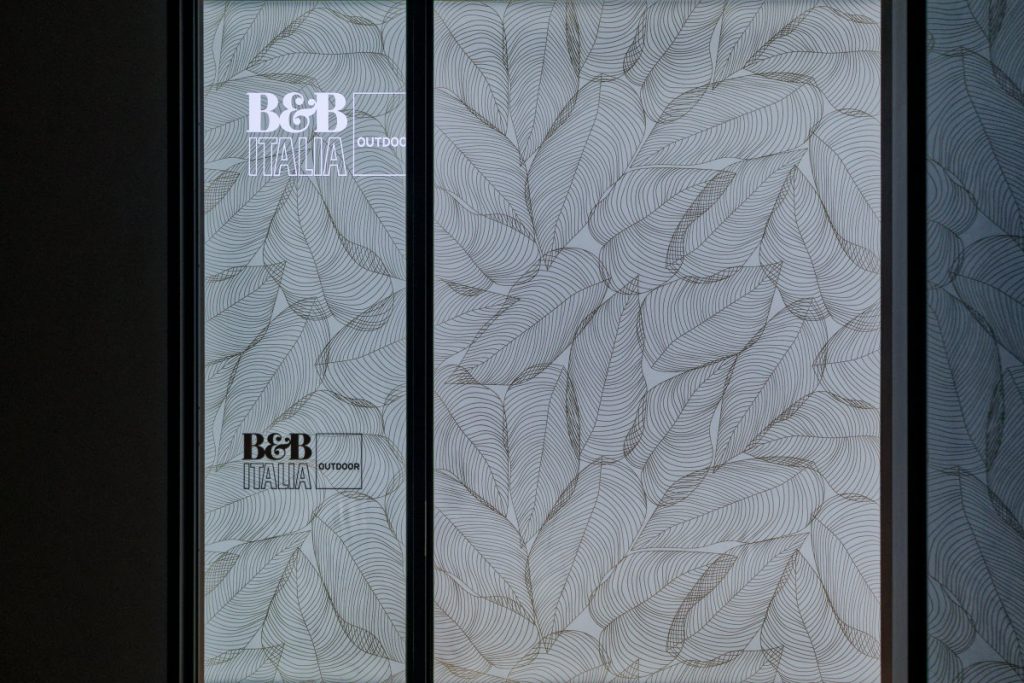B&B Italia Outdoorのブランドロゴと植物の葉を描いたグラフィックが施されたショールームのガラス面