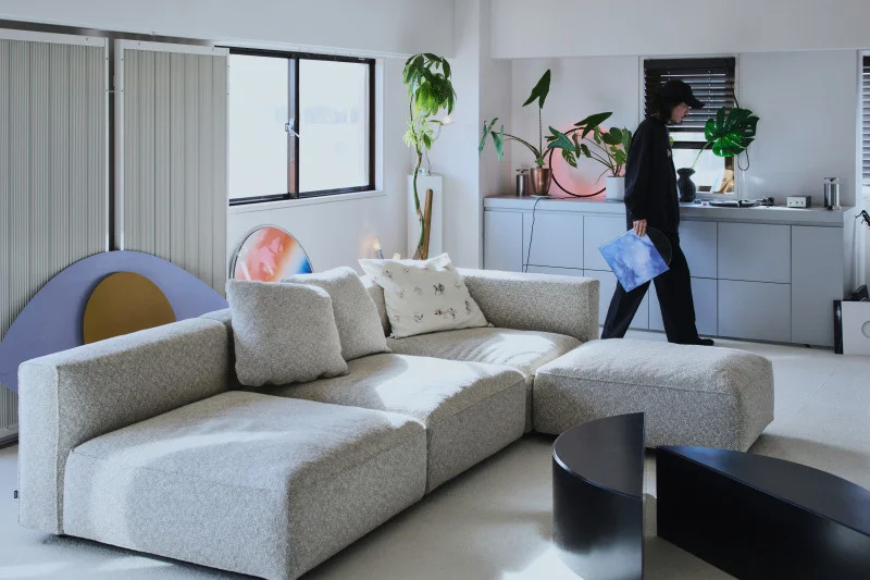 明るいリビングに置かれたグレーの大型ソファと観葉植物。現代的な住空間のインテリア